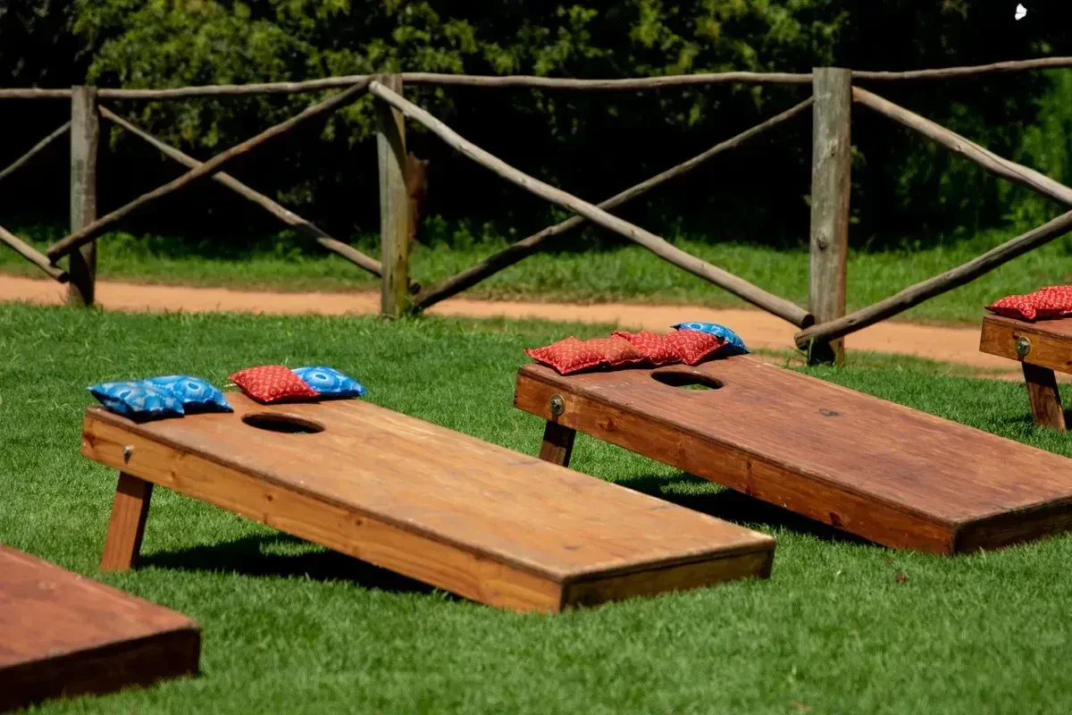 Cornhole boards with bean bags set up on a green lawn in the sunshine