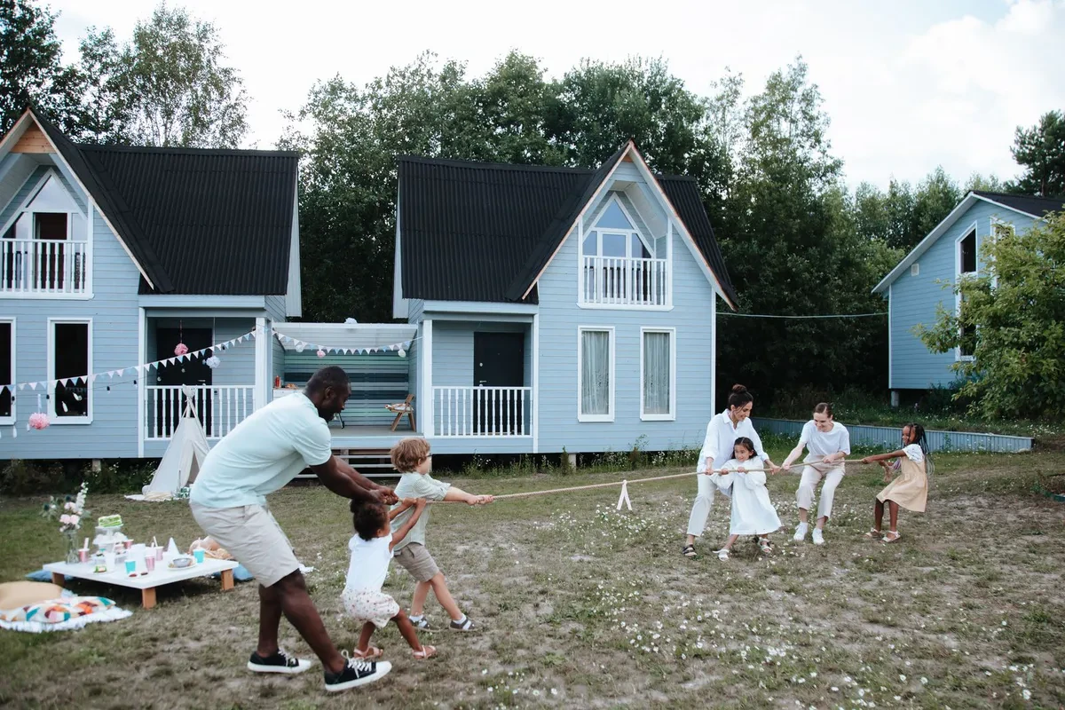Family playing tug of war on the lawn between houses on a sunny afternoon