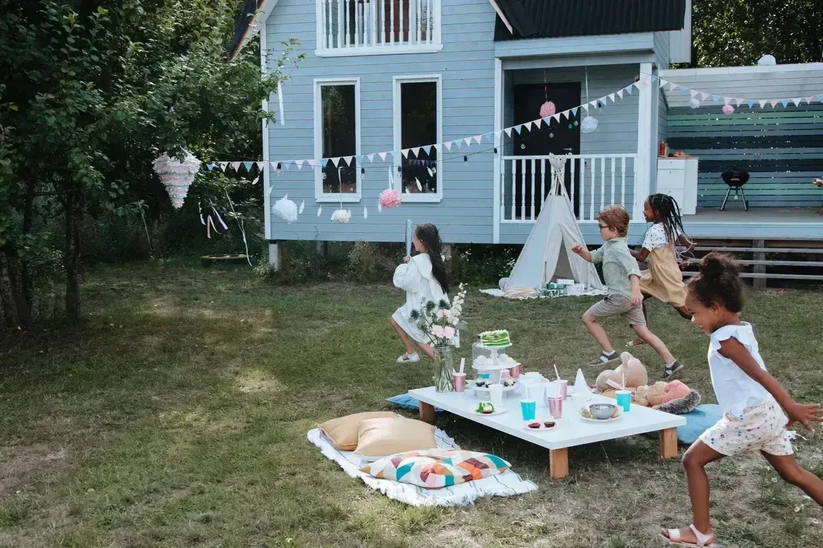 Children chasing a pinata hanging from a tree at an outdoor birthday party