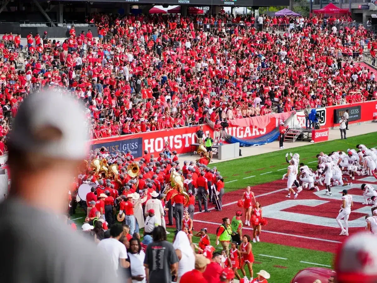 Football fans in team colors cheering together in the stands on game day